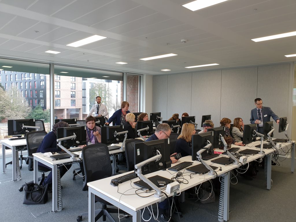 Image shows people sat at computers in a training room